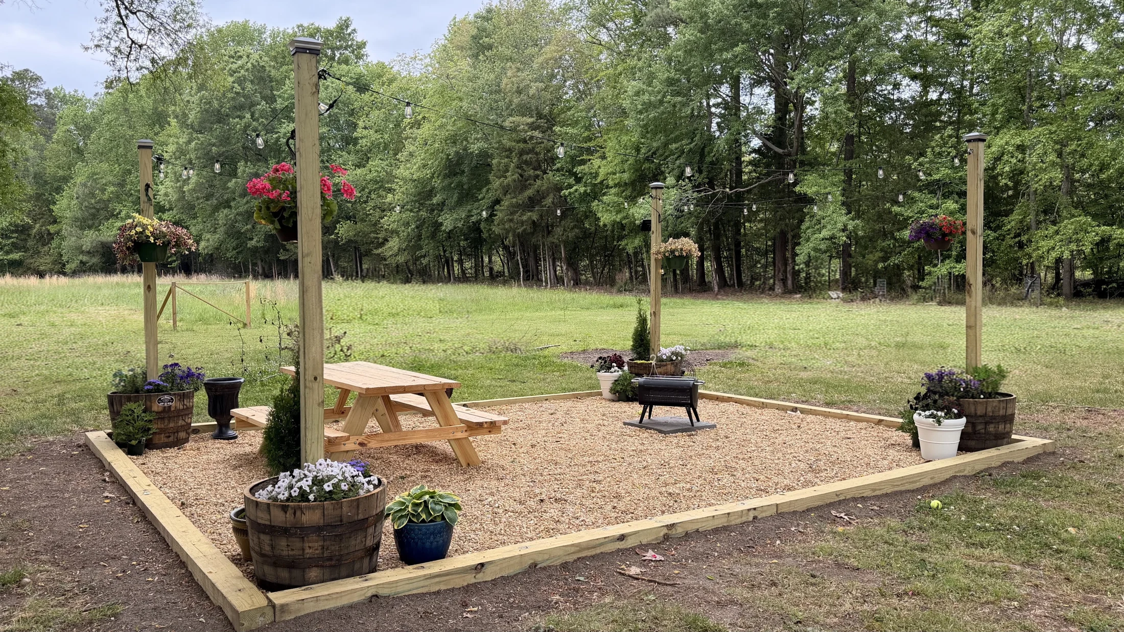 Gravel outdoor seating area with flowers and string lights