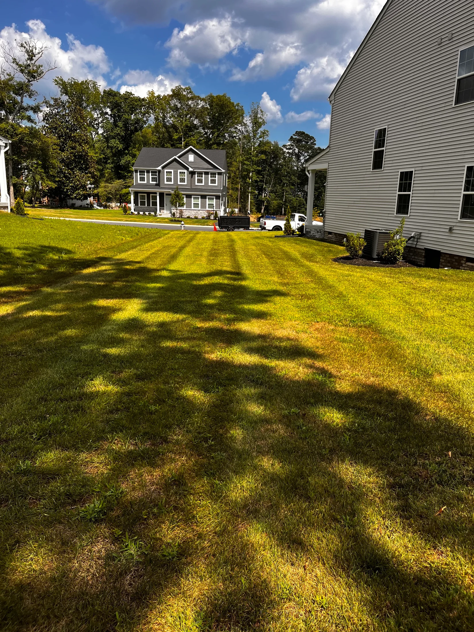 Residential lawn beside a home with landscape equipment in the distance
