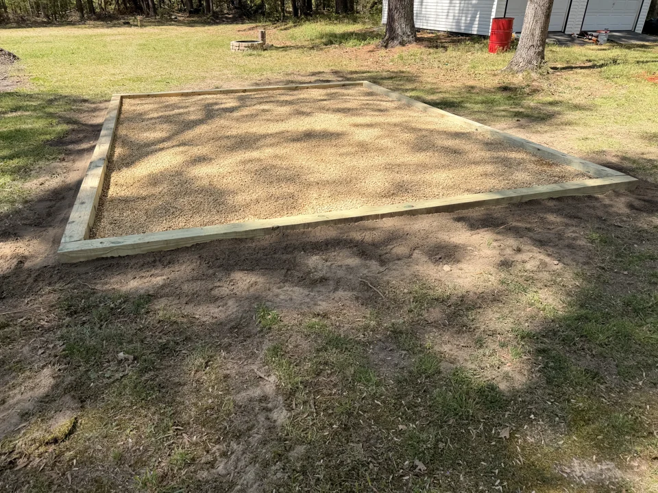Rectangular timber-framed aggregate pad beside a lawn and trees