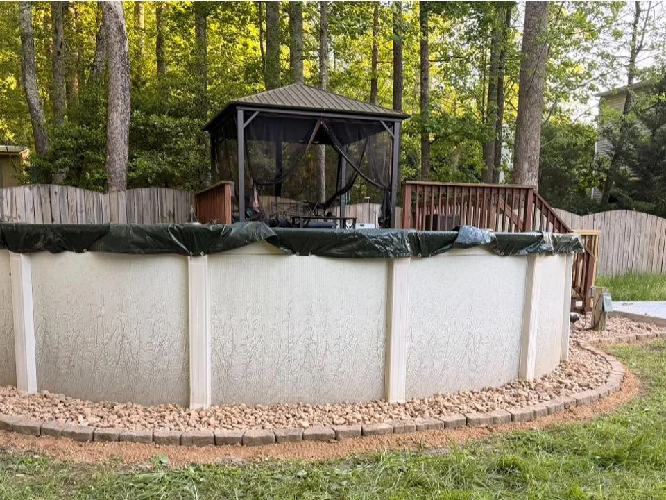 Pale decorative stone and block edging around an existing above-ground pool