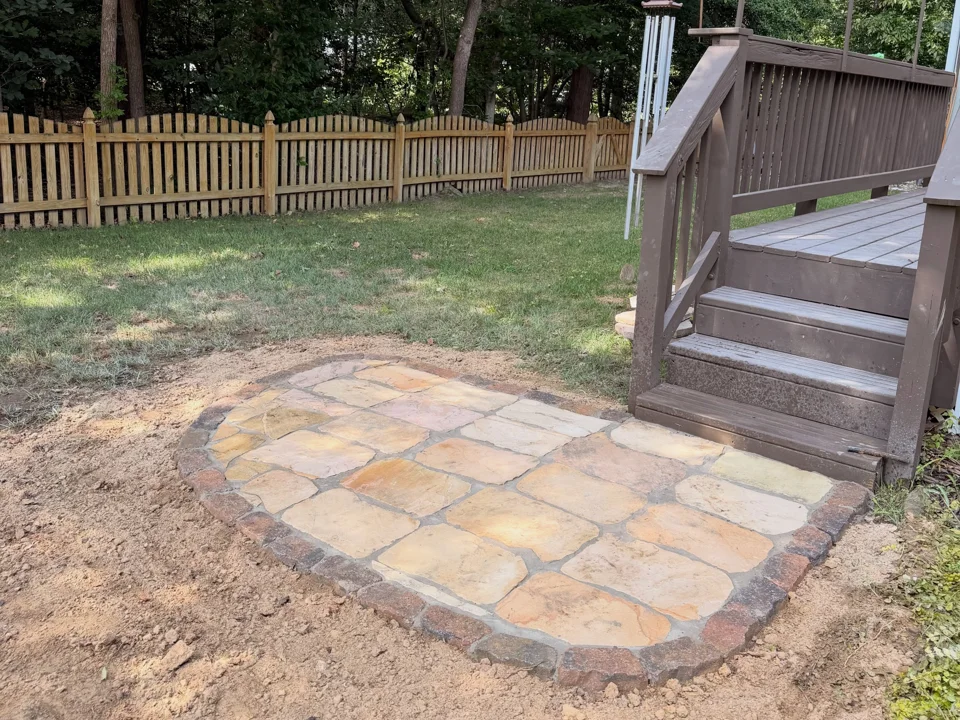 Natural stone landing with a block border at the foot of wooden steps