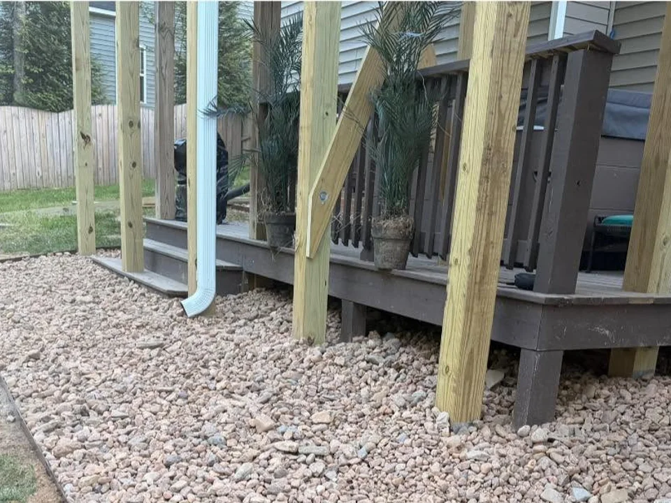 Pale decorative stone and metal edging beneath an existing raised deck